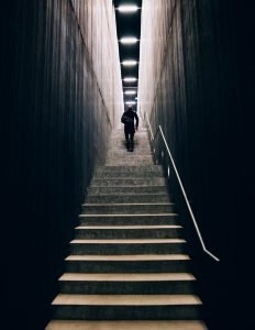 man in black pants going down stairs