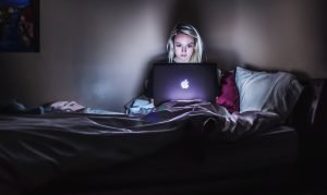 woman sitting on bed with MacBook on lap